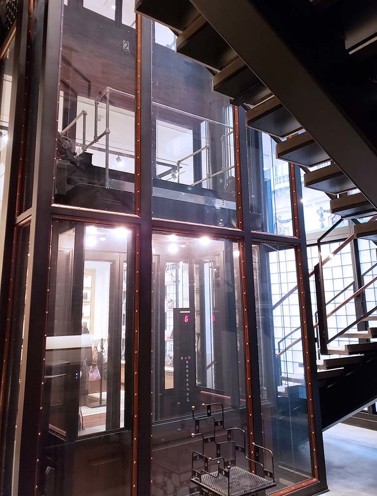 Coach custom glass elevator integrated into the stairway